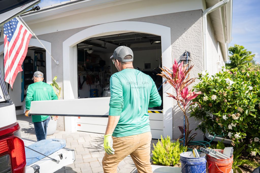 Emerald Green crew carrying a flood barrier plank at a Southwest Florida home