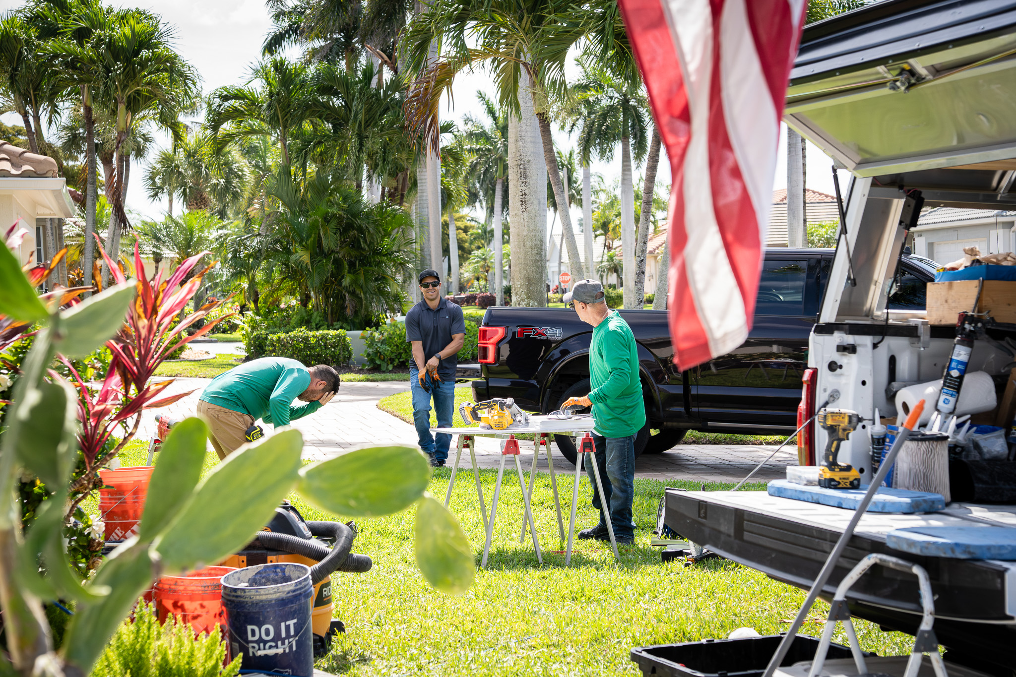 Emerald Green crew working on site at a Southwest Florida home, trucks and equipment staged in the driveway